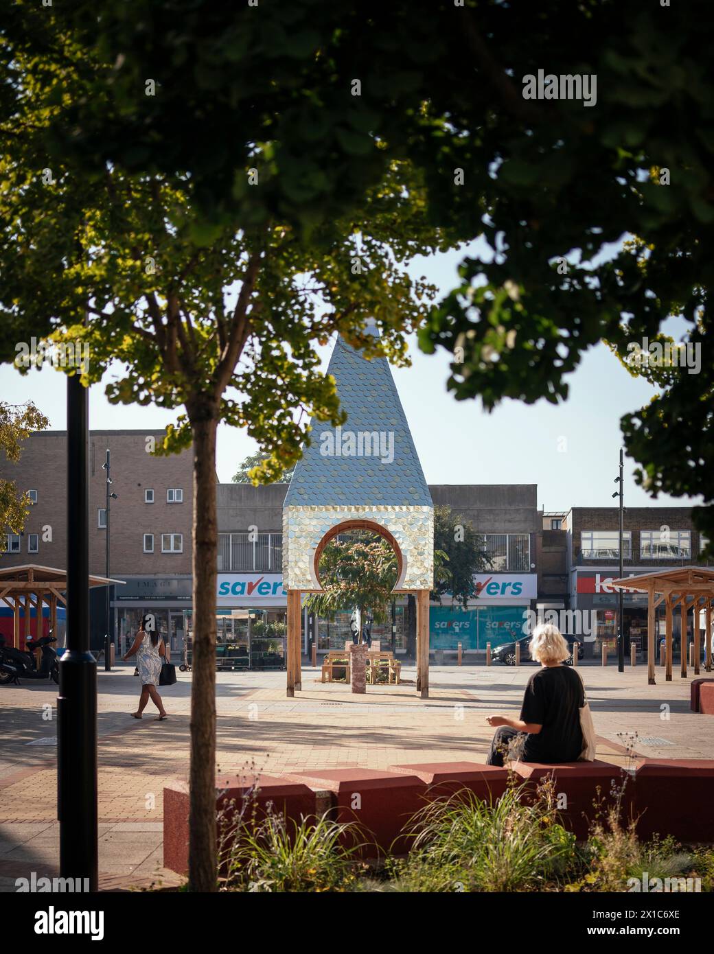 Bermondsey Market Place, padiglione della torre dell'orologio in argento al centro con fogliame in primo piano. The Blue, Londra, Regno Unito. Architetto: Assemblare Un Foto Stock