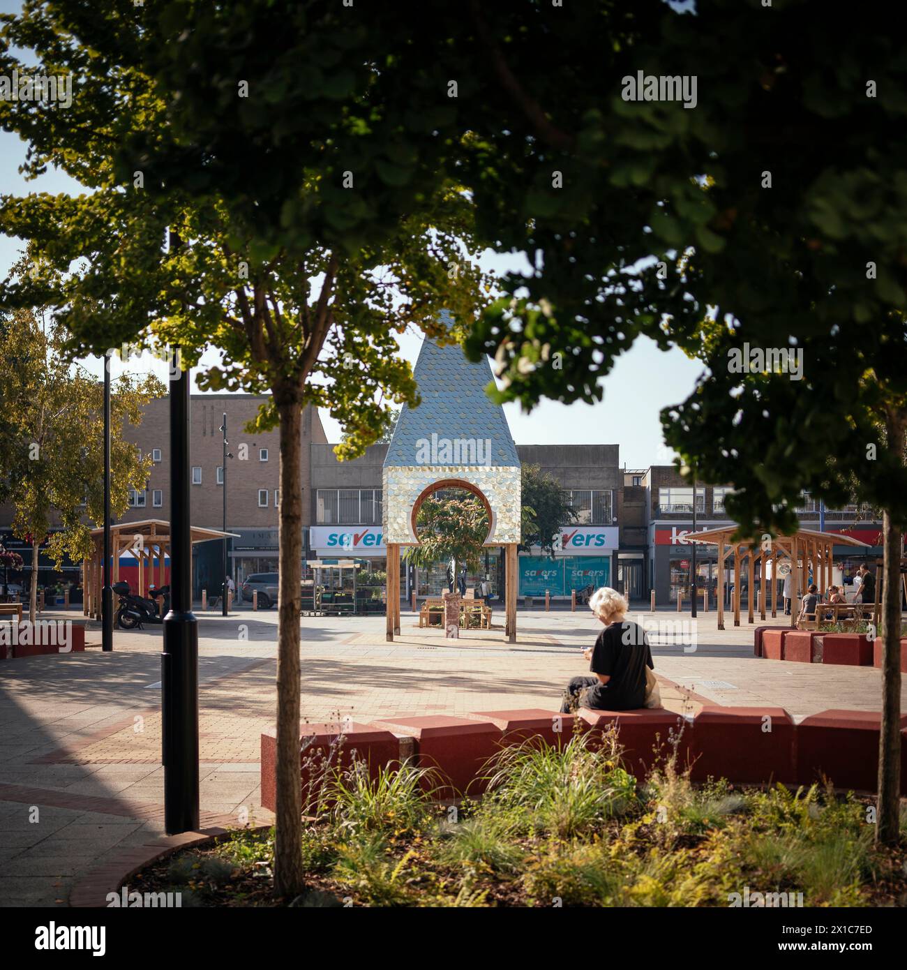 Bermondsey Market Place, padiglione della torre dell'orologio in argento al centro con fogliame in primo piano. The Blue, Londra, Regno Unito. Architetto: Assemblare Un Foto Stock