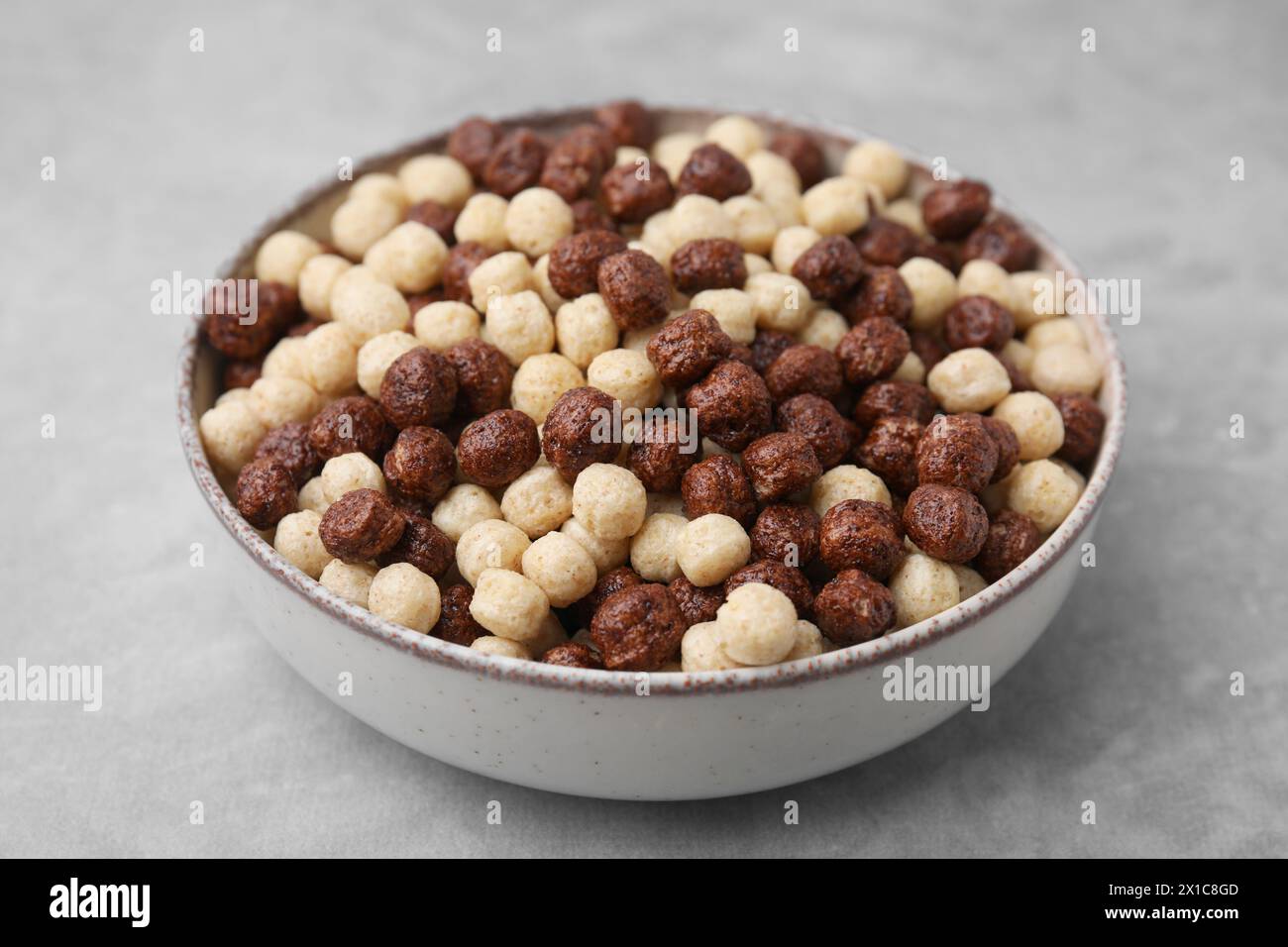 Gustose palline di cereali nel recipiente sul tavolo grigio, primo piano Foto Stock