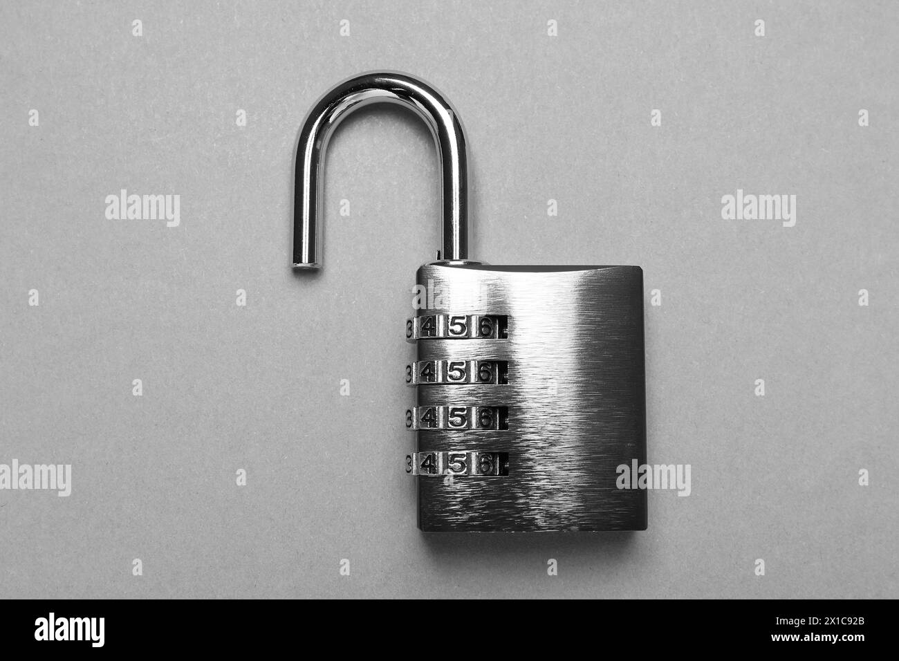 Un lucchetto a combinazione in acciaio su sfondo grigio, vista dall'alto Foto Stock