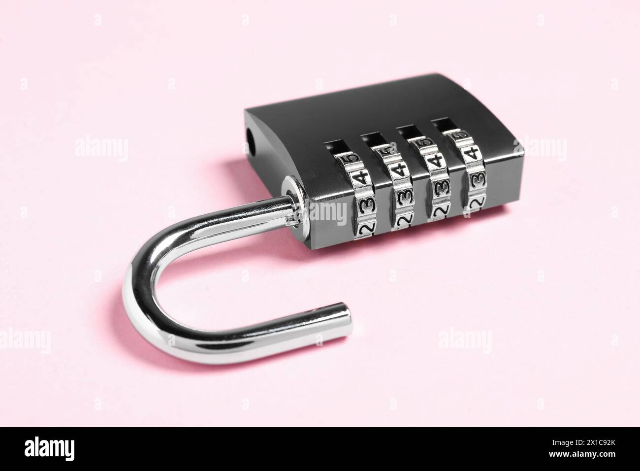 Un lucchetto combinato in acciaio su sfondo rosa, primo piano Foto Stock