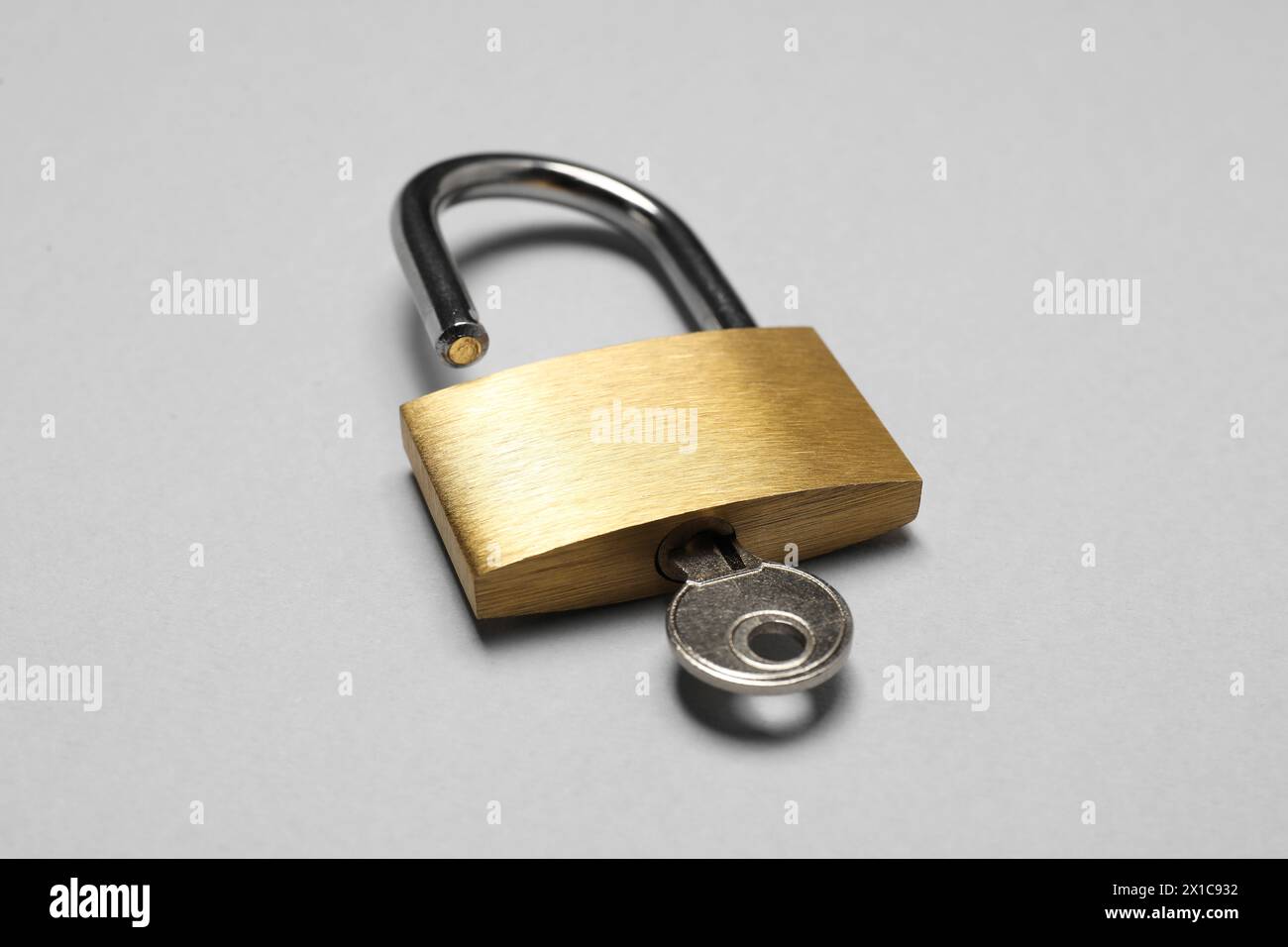 Lucchetto in acciaio con chiave su sfondo grigio, primo piano Foto Stock