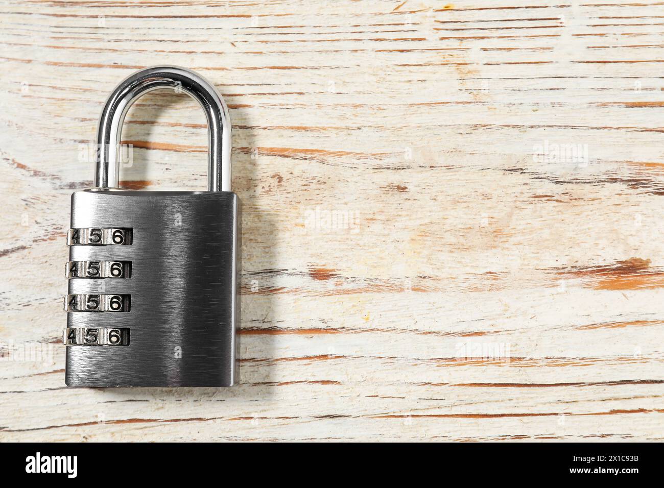 Un lucchetto combinato in acciaio su un tavolo in legno chiaro, vista dall'alto. Spazio per il testo Foto Stock