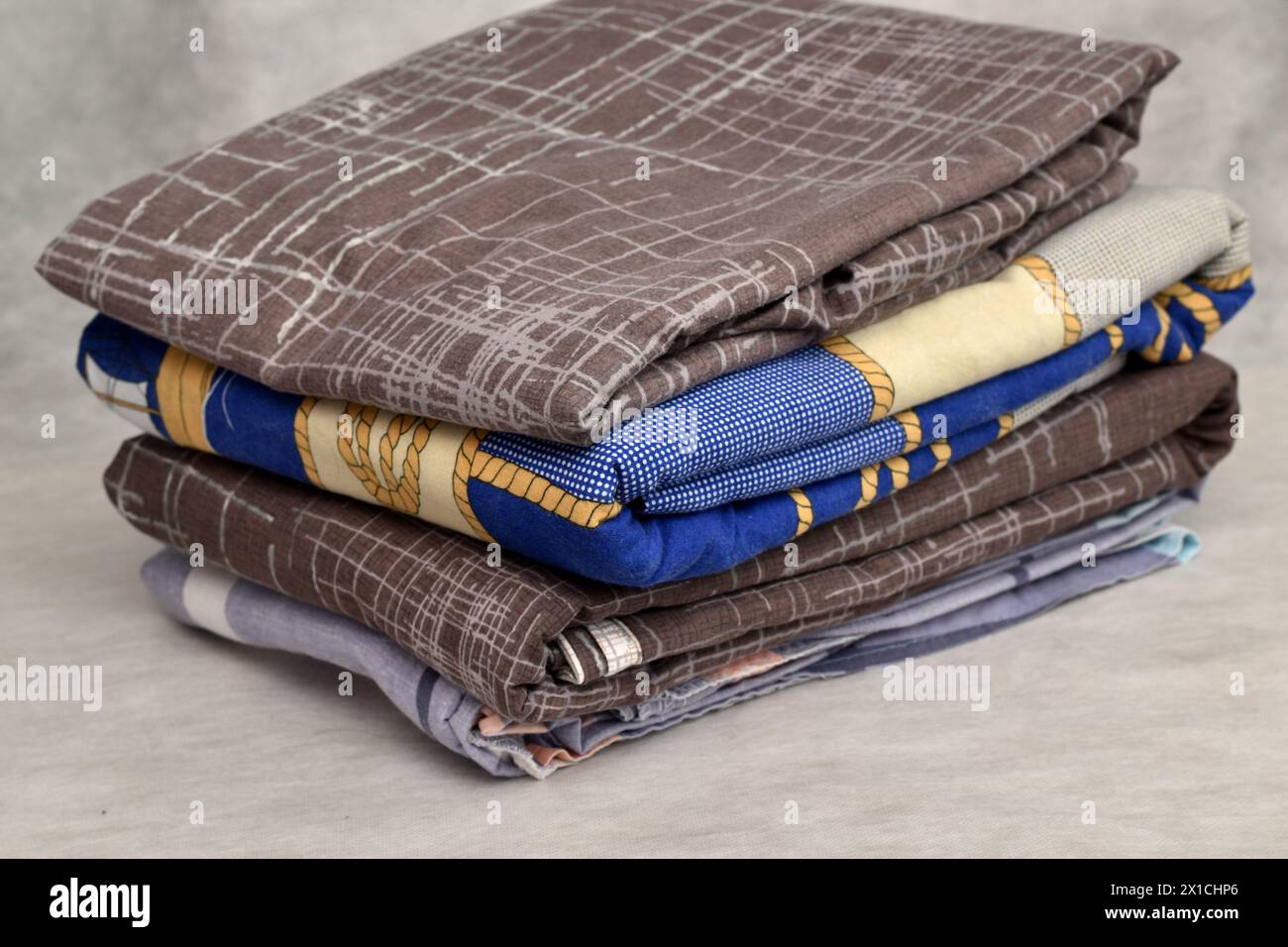 Primo piano di una pila di biancheria da letto, lenzuola, federazioni su sfondo chiaro. Foto Stock