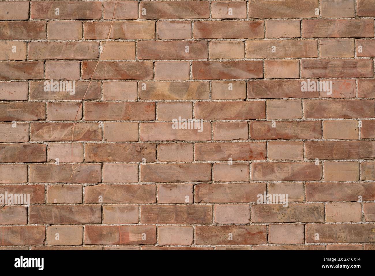 Le trame delle pareti in mattoni creano un motivo che si estende orizzontalmente e verticalmente lungo la parete. Le sfumature di rosso, variate dal tempo e dall'usura, aggiungono profondità a. Foto Stock