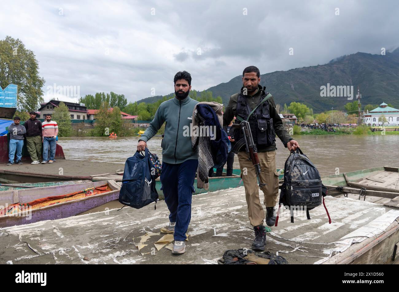 Un poliziotto e un poliziotto locale portano borse scolastiche e oggetti personali di persone annegate dopo averli recuperati dal fiume Jhelum seguendo una barca che si stava ribaltando a Srinagar. Una barca che trasportava sei individui, tra cui una donna e i suoi due fratelli, si capovolse mentre attraversava il fiume Jhelum a Srinagar. La barca, che trasportava almeno 15 persone, per lo più bambini, ha provocato sei morti, con tre persone ancora scomparsi. Le piogge continue negli ultimi due giorni, che hanno portato a un aumento del livello dell'acqua nel fiume Jhelum, hanno portato alla tragedia. Foto Stock