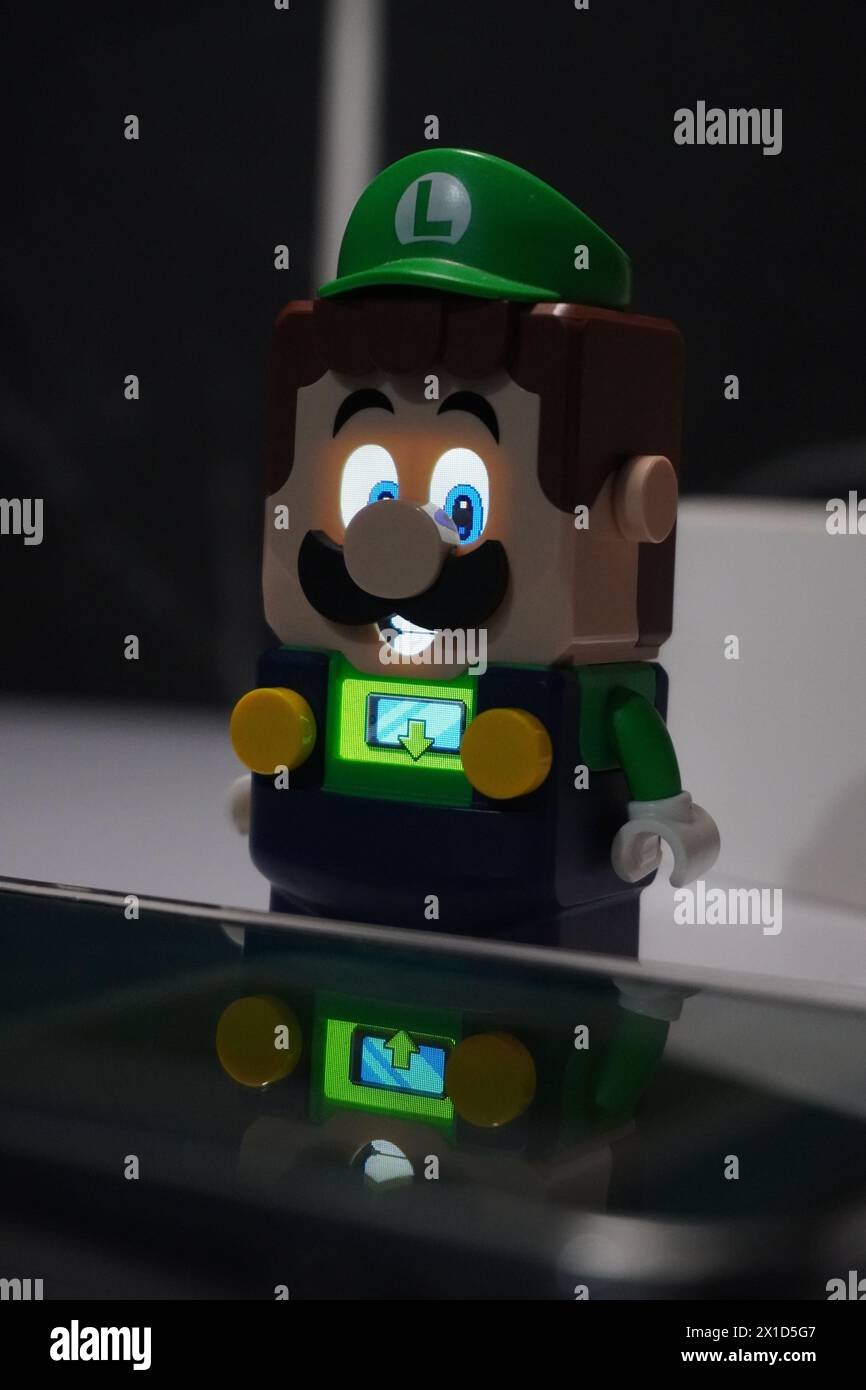 Una figura di Luigi del cartone animato di Super Mario Bros che si illumina e si trova vicino ad un cellulare illuminato Foto Stock