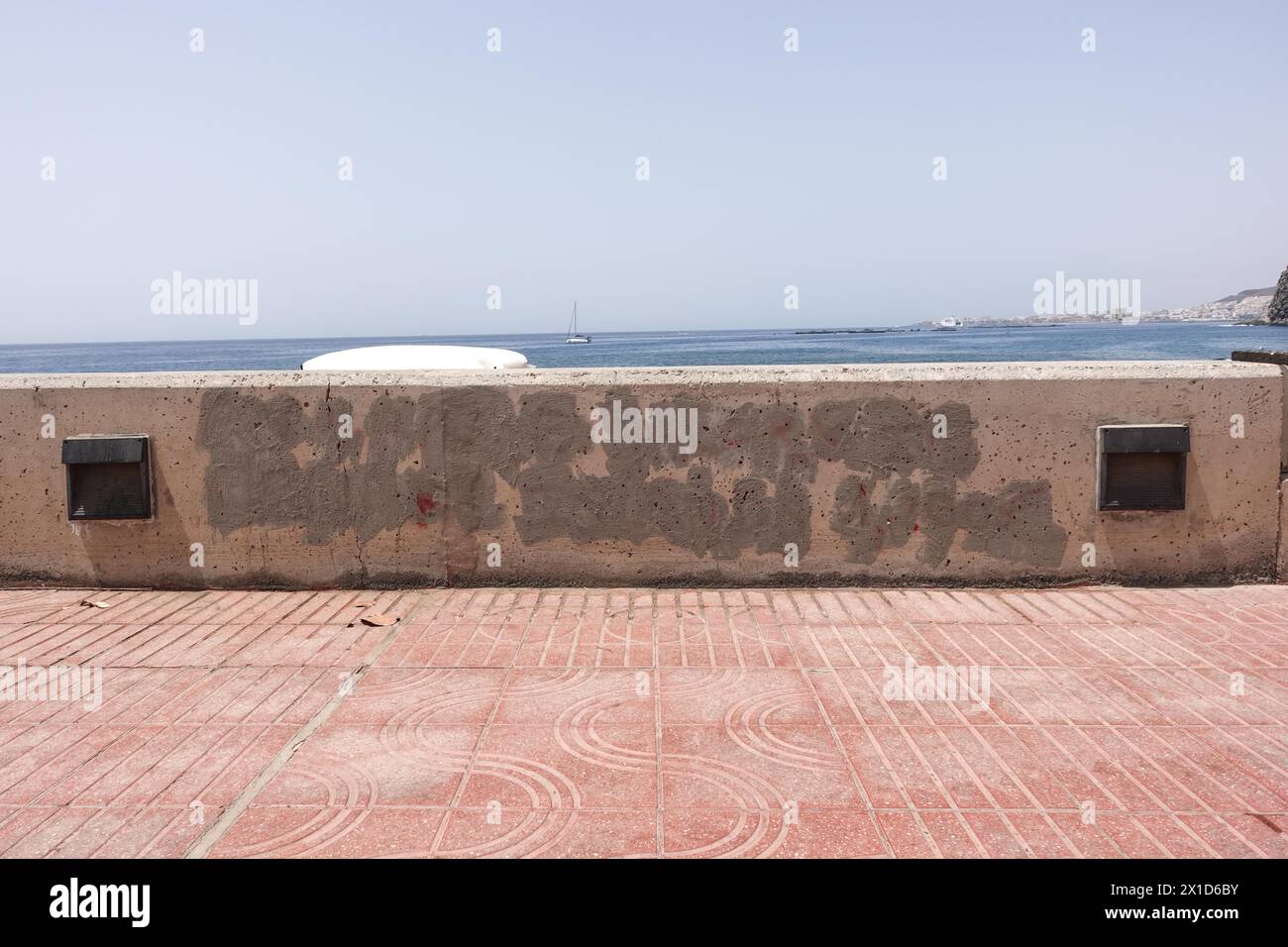 Palm-Mar, Tenerife, 16 aprile 2024 - a Palm-Mar, Tenerife, i funzionari hanno dipinto a Palm-Mar, Tenerife, i graffiti che una volta hanno detto "stipendio medio nelle Isole Canarie 1.200E". - Graffiti antituristici incastonati sulle pareti della località balneare di Palm-Mar nel sud dell'isola di Tenerife sono stati dipinti da funzionari che stanno cercando di trasmettere la piccola città come "turistico amichevole" diversi messaggi sono stati spruzzati settimane fa su pareti e panchine, tuttavia, la nuova vernice bianca copre ora le aree colpite e uno slogan che recita "stipendio medio nelle Isole Canarie 1.200E” è stato ora coperto di vernice grigia. Credi Foto Stock