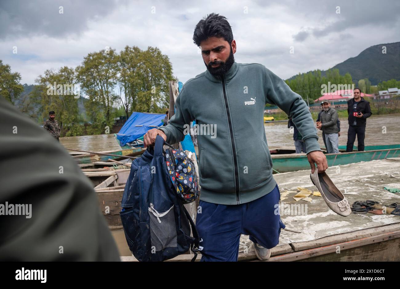 Un uomo porta una borsa scolastica e gli effetti personali delle persone annegate dopo averle recuperate dal fiume Jhelum, seguendo una barca che si stava ribaltando a Srinagar. Una barca che trasportava sei individui, tra cui una donna e i suoi due fratelli, si capovolse mentre attraversava il fiume Jhelum a Srinagar. La barca, che trasportava almeno 15 persone, per lo più bambini, ha provocato sei morti, con tre persone ancora scomparsi. Le piogge continue negli ultimi due giorni, che hanno portato a un aumento del livello dell'acqua nel fiume Jhelum, hanno portato alla tragedia. (Foto di Idrees Abbas/SOPA Images/Sipa USA) Foto Stock