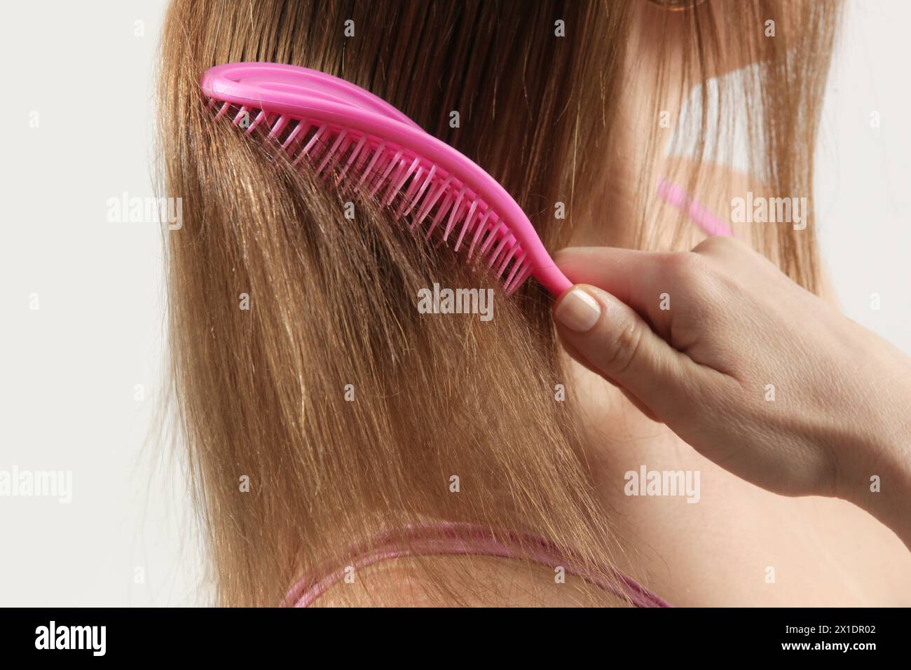 Cura dei capelli. Vista ravvicinata della donna bruna che pettina i capelli asciutti danneggiati con una spazzola in plastica. Foto Stock