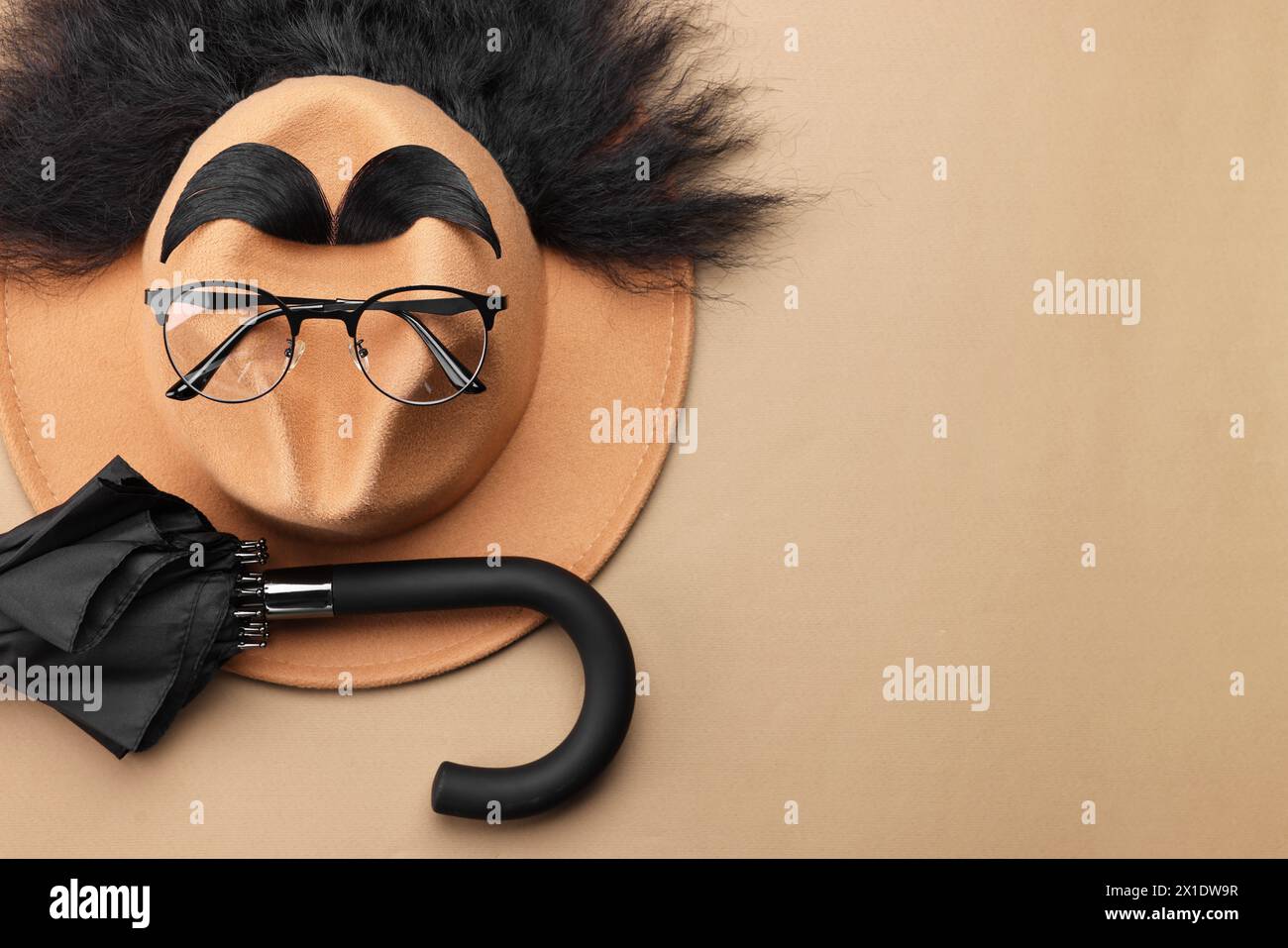 Il viso dell'uomo è fatto di capelli artificiali, sopracciglia, occhiali e cappello su sfondo beige, vista dall'alto. Spazio per il testo Foto Stock
