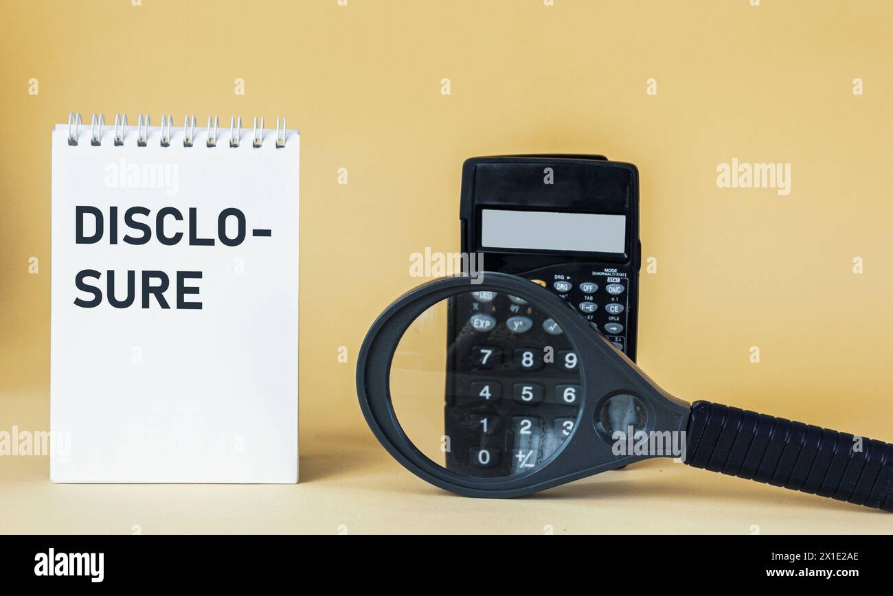 La parola DIVULGAZIONE scritta in un blocco note. Lente di ingrandimento e calcolatrice su sfondo giallo Foto Stock