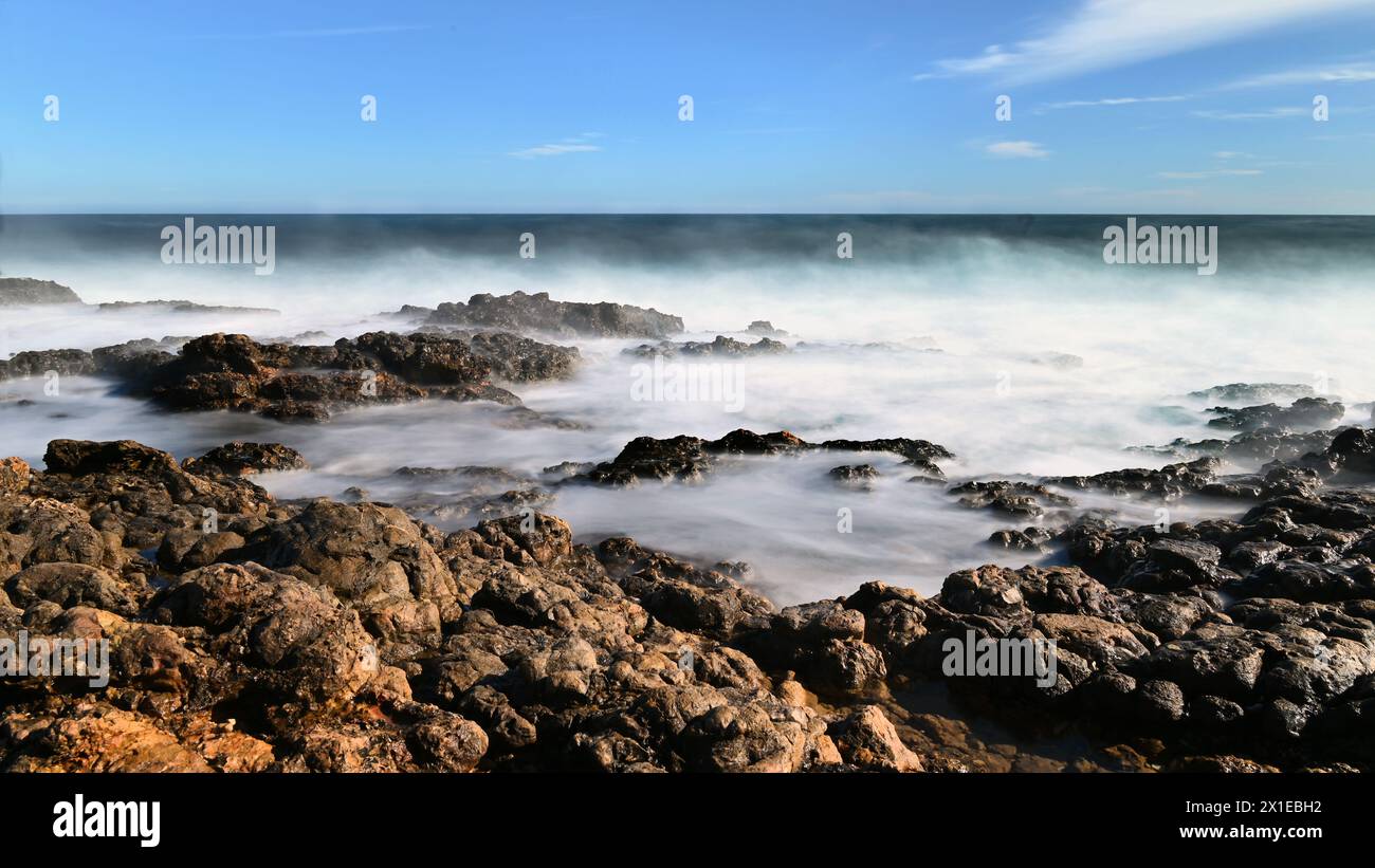 Onde nebbiose che si infrangono sulla costa rocciosa di Cap d'Antibes con esposizione prolungata in grande formato Foto Stock
