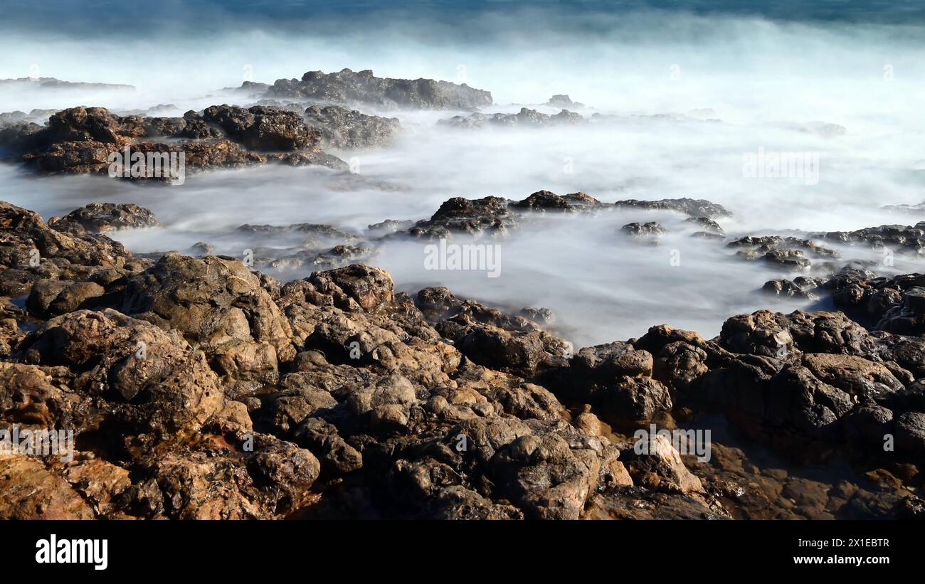 Onde nebbiose che si infrangono sulla costa rocciosa di Cap d'Antibes con esposizione prolungata in grande formato Foto Stock