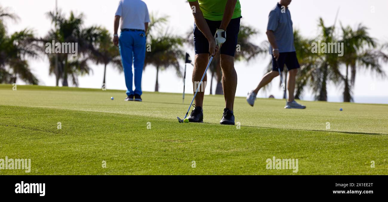 Il golfista pratica sul putting green con un ferro da stiro, al primo semaforo del mattino. Foto Stock