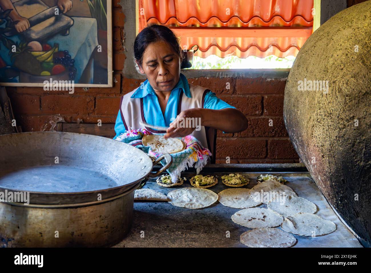 Una donna anziana che cucina tortilla di mais su un tradizionale piano cottura. Oaxaca, Messico. Foto Stock