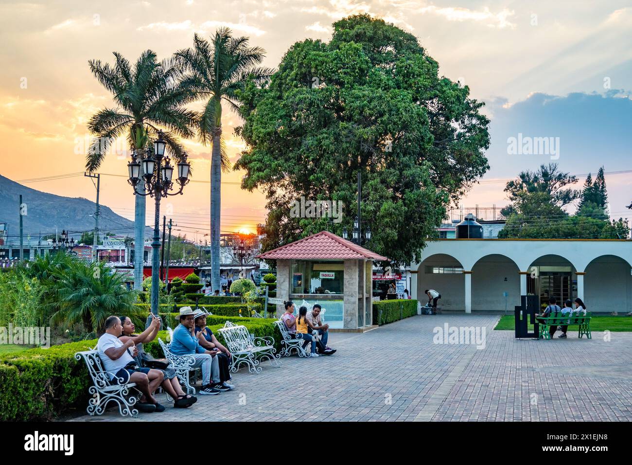 La gente gode di un bellissimo tramonto nel centro della cittadina di Santa María del Tule, Oaxaca, Messico. Foto Stock