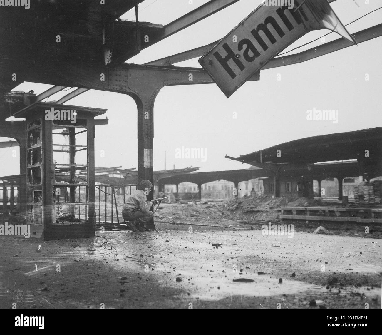 Allerta per il movimento nemico, un privato di prima classe accovacciato con una carabina alla stazione ferroviaria nella città appena catturata di Hamm, Germania ca. 6 aprile 1945 Foto Stock