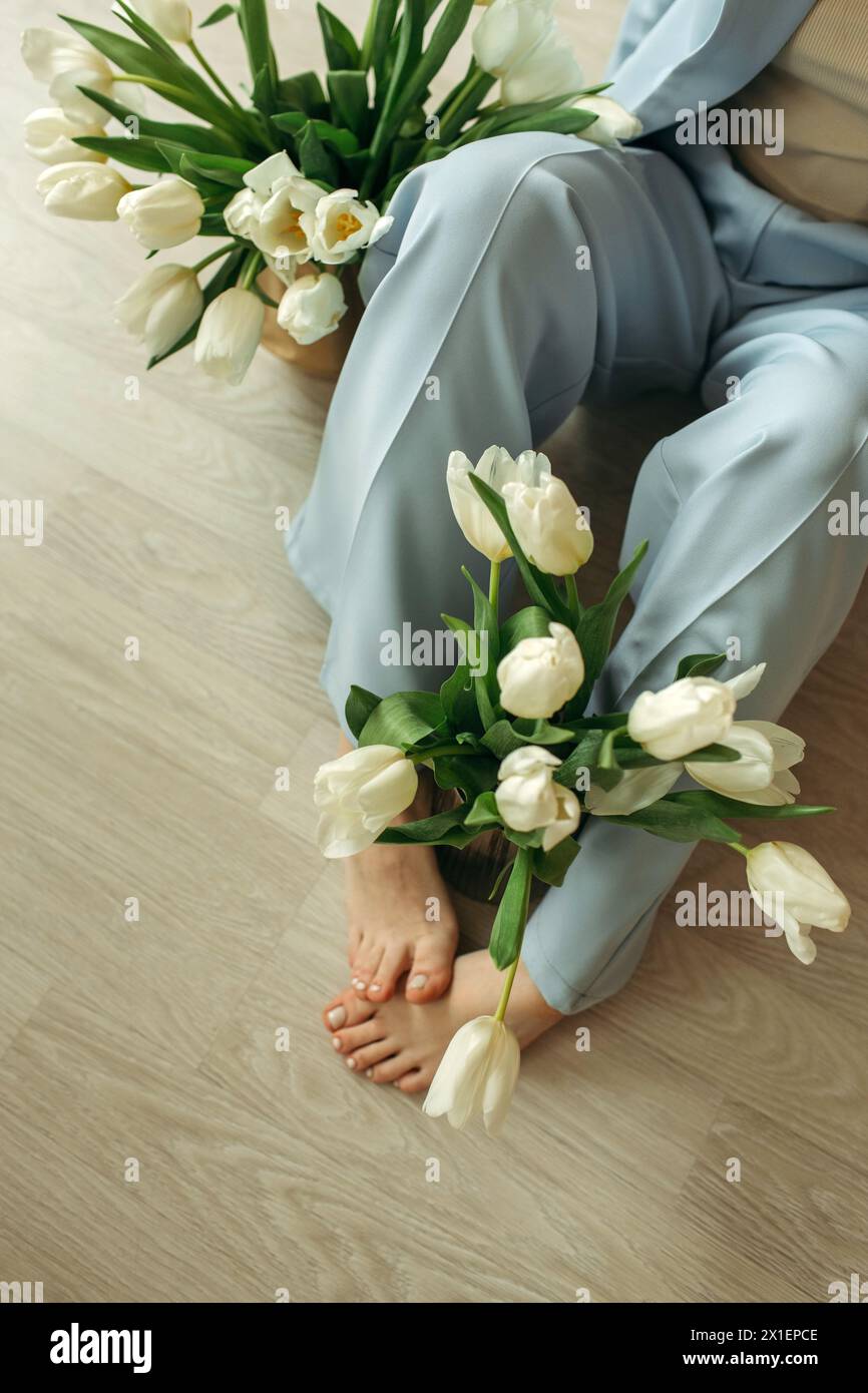 Una donna è seduta sul pavimento, tenendo in mano un mazzo di fiori. Foto Stock