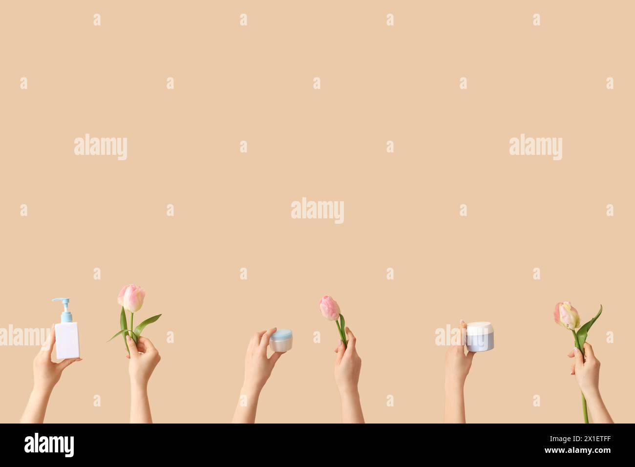 Donne con prodotti cosmetici e tulipani su sfondo beige Foto Stock