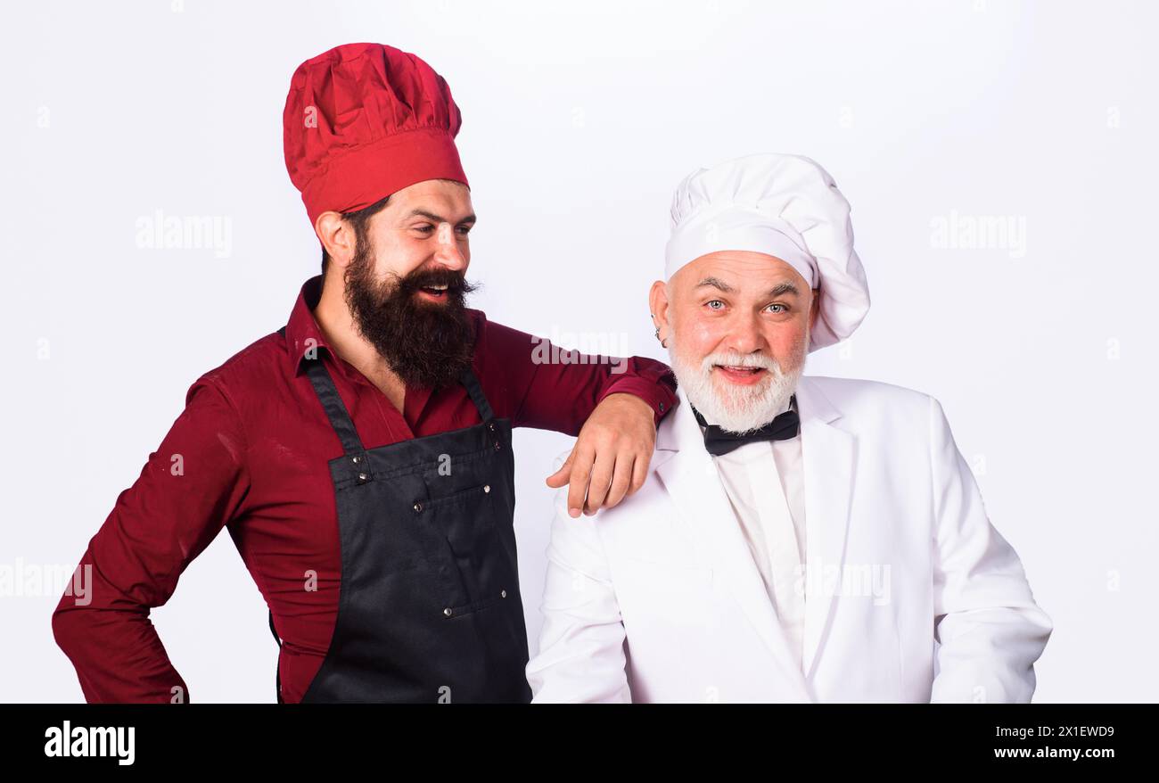 Due cuochi professionisti preparano il pasto nella cucina del ristorante. Cuochi professionisti in uniforme. Cuoco capo o fornaio e cucina professionale. Maschio Foto Stock