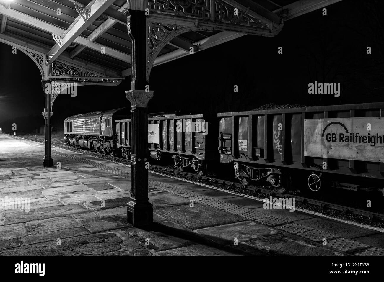 Locomotiva GB Rail Freight classe 66 66718 sotto la copertura della Midland Railway alla stazione ferroviaria di Hellifield con un treno che trasporta aggregati di notte Foto Stock