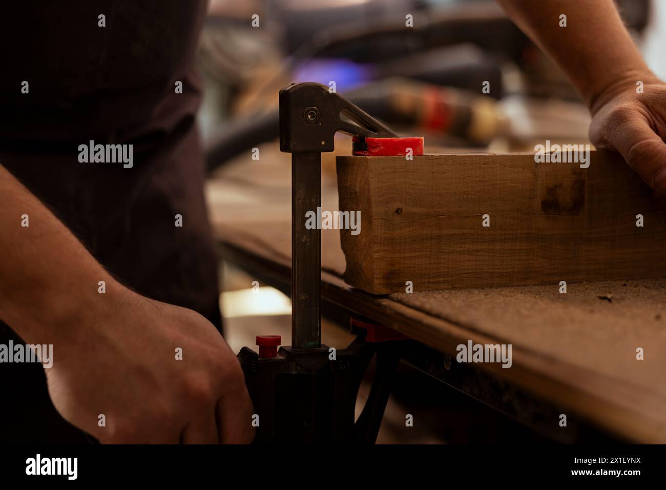 Falegname con morsa da banco per bloccare blocchi di legno, iniziare il montaggio dei mobili in officina, primo piano. Produttore di falegnameria che utilizza una morsa per afferrare il pezzo di legno prima di intagliarlo Foto Stock