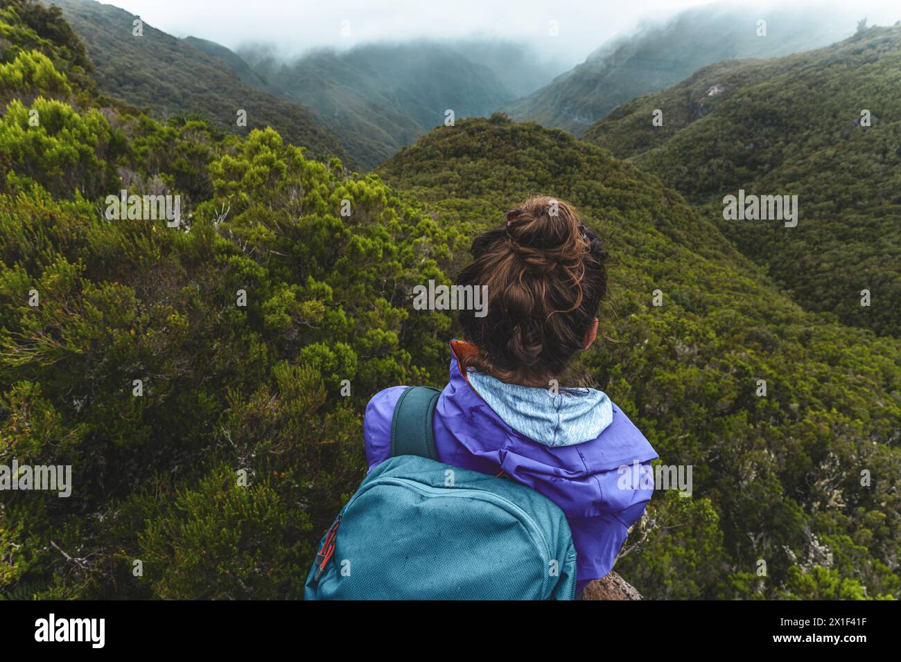 Descrizione: Ripresa dall'angolo superiore di una turista con zaino che gode della vista su una valle sovrastata in una giornata nebbiosa e nuvolosa. 25 Fontes, Mad Foto Stock