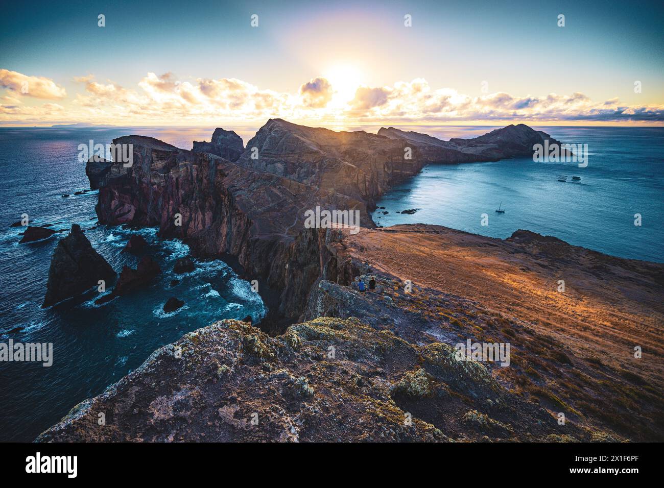 Descrizione: Una coppia di turisti fotografa l'alba sulle colline pedemontane di un'isola vulcanica e dell'Oceano Atlantico. São Lourento, Isola di Madeira, P. Foto Stock