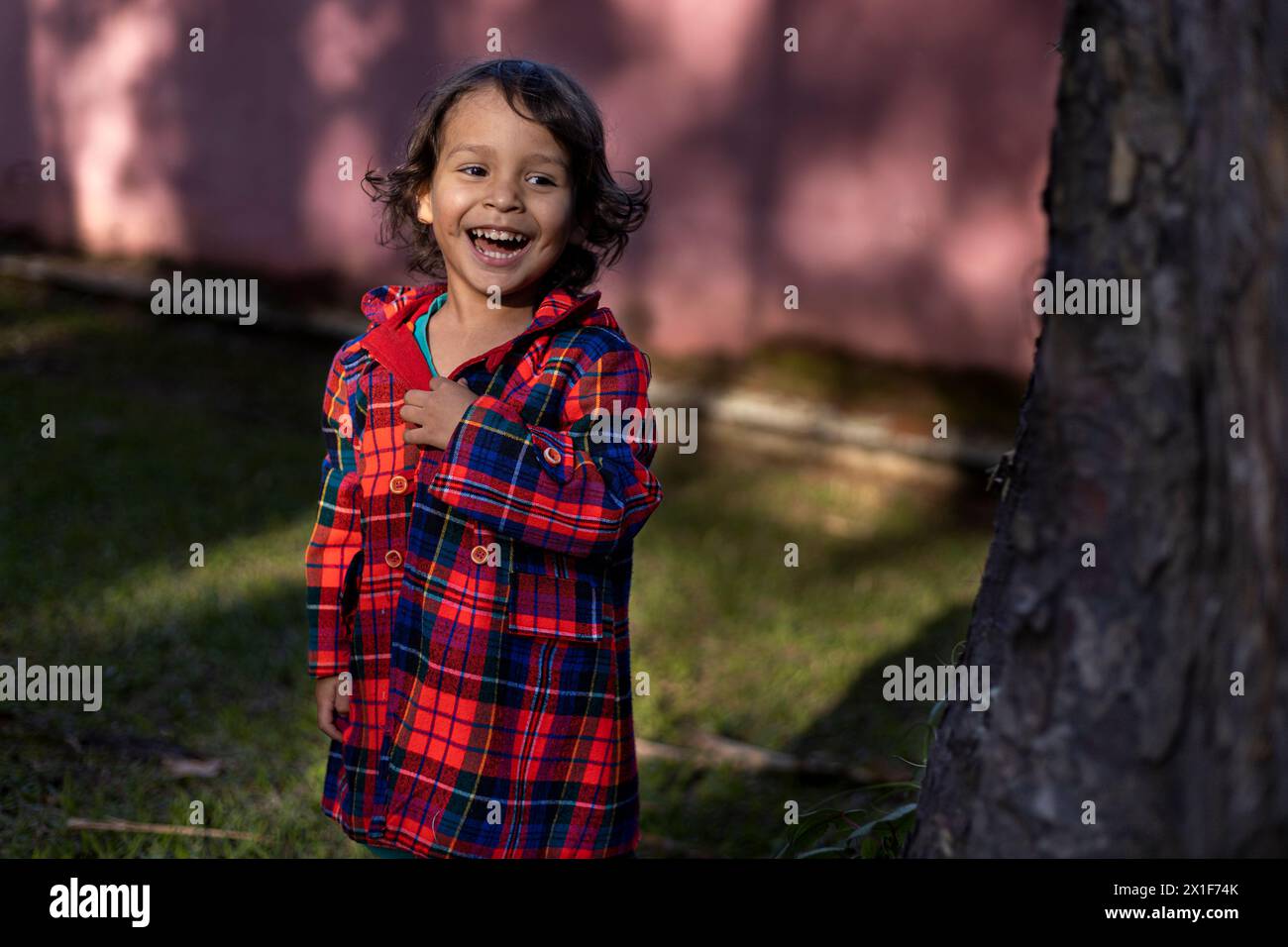 Il bambino latino-americano ride felicemente mentre si gode il pomeriggio nel parco. Concetto di famiglia e felicità. Foto Stock