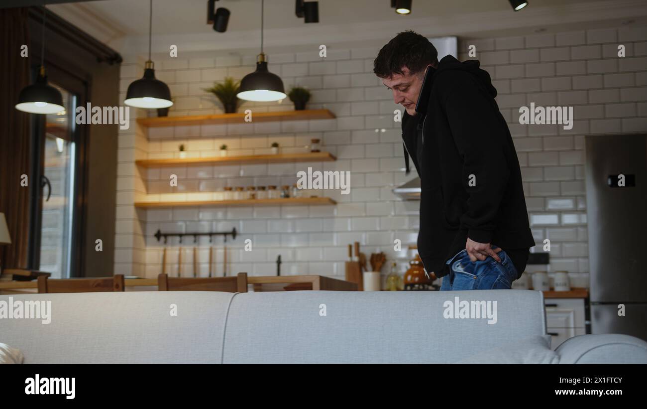 L'uomo che ha fretta di andare al lavoro, indossare jeans e parlare al telefono, si prepara rapidamente al lavoro. Foto Stock