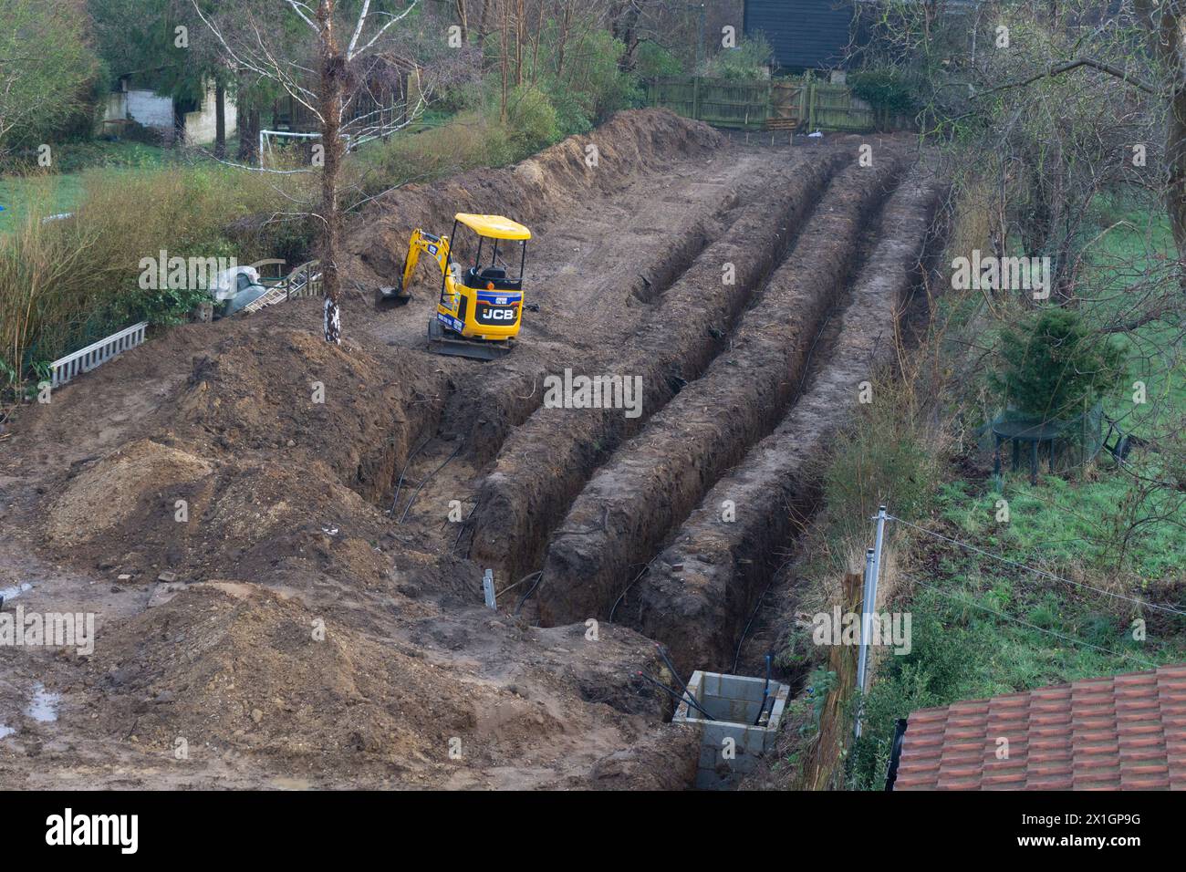 giardino residenziale scavato sul retro con miniescavatore per impianto di riscaldamento a pompa di calore a terra Foto Stock
