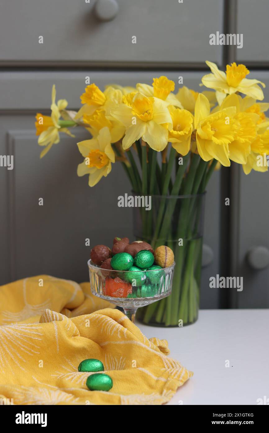 Bouquet di narcisi dorati in vaso di vetro su sfondo verde in legno con spazio per il testo. Foto Stock