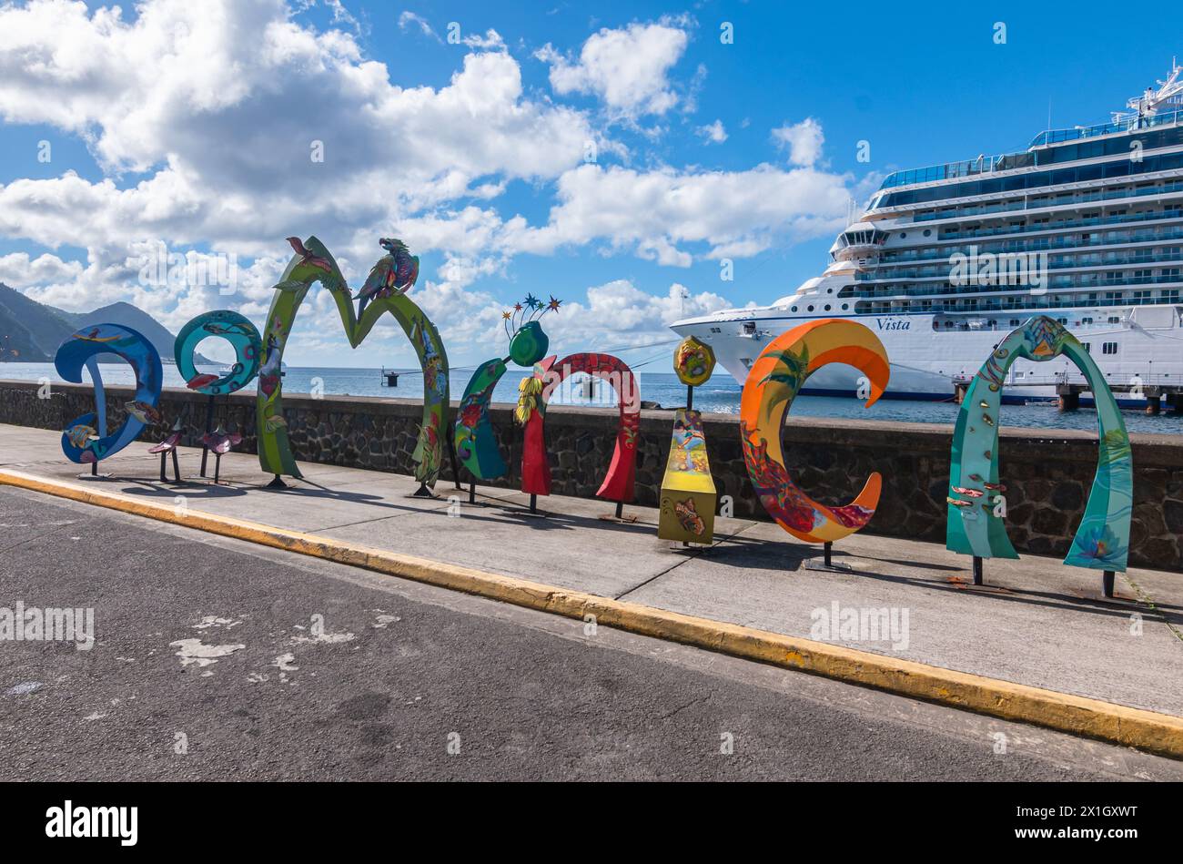 Roseau, Dominica - 24 novembre 2023: Cartello con la parola Dominica di fronte alla nave Oceania Cruises Vista nel porto crocieristico di Roseau. Foto Stock