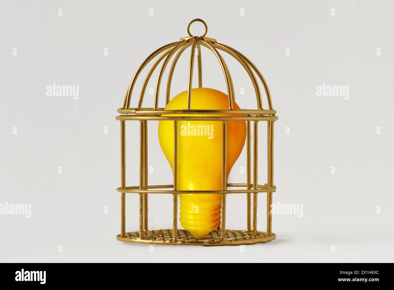 Lampadina gialla in gabbia per uccelli su sfondo bianco - concetto di mente e libertà Foto Stock