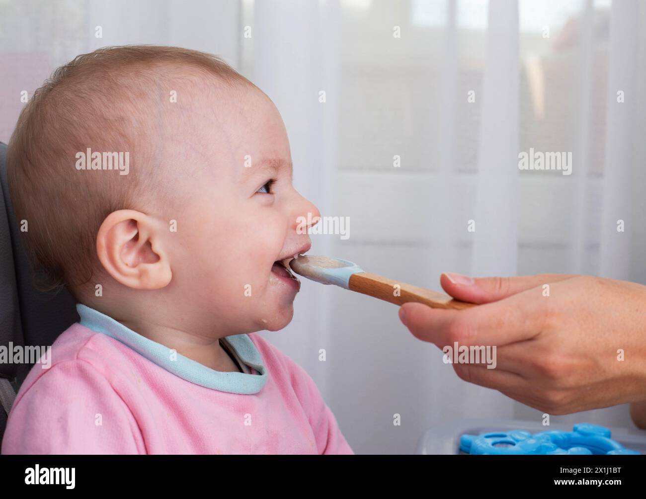 La mano di una madre con un cucchiaio e porridge di grano saraceno nutre un bambino di un anno. Nutrizione dei bambini in tenera età. Alimenti per bambini. Copia Foto Stock