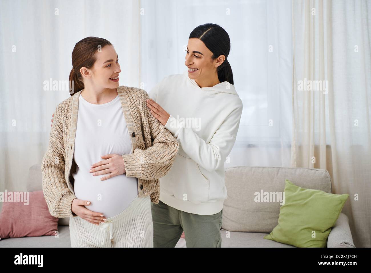 Una donna incinta siede su un divano accanto al suo allenatore durante i corsi dei genitori, mentre un'altra donna sta al suo fianco. Foto Stock