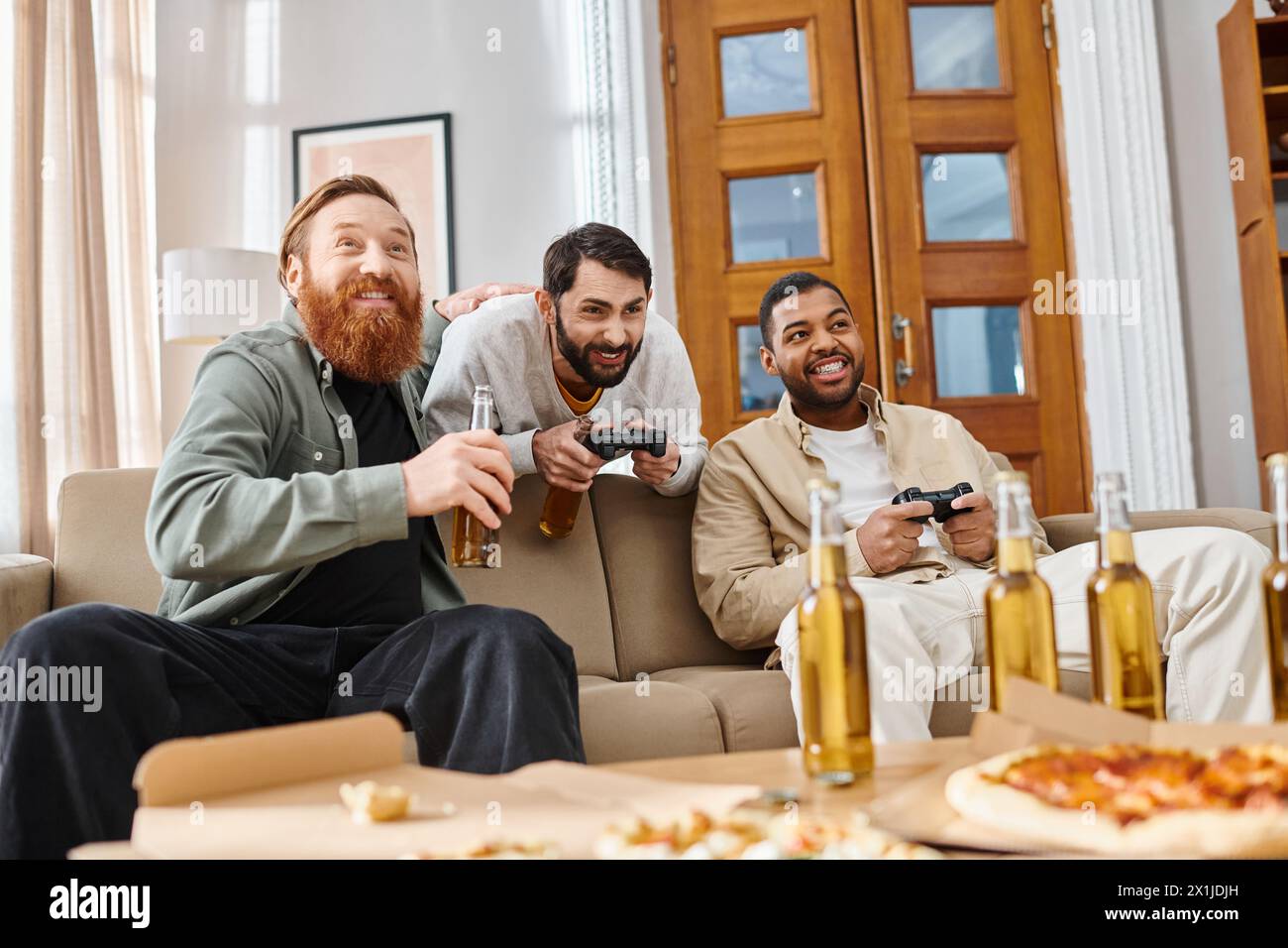 Tre bellissimi uomini di diverse razze condividono sorrisi e chiacchierate intorno a un tavolo pieno di pizza e birra, godendosi una serata rilassata di amicizia Foto Stock