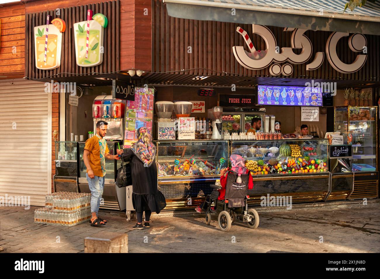 Le donne iraniane acquistano succo di frutta e gelato appena spremuto da un venditore ambulante a New Julfa, quartiere armeno di Isfahan, Iran. Foto Stock
