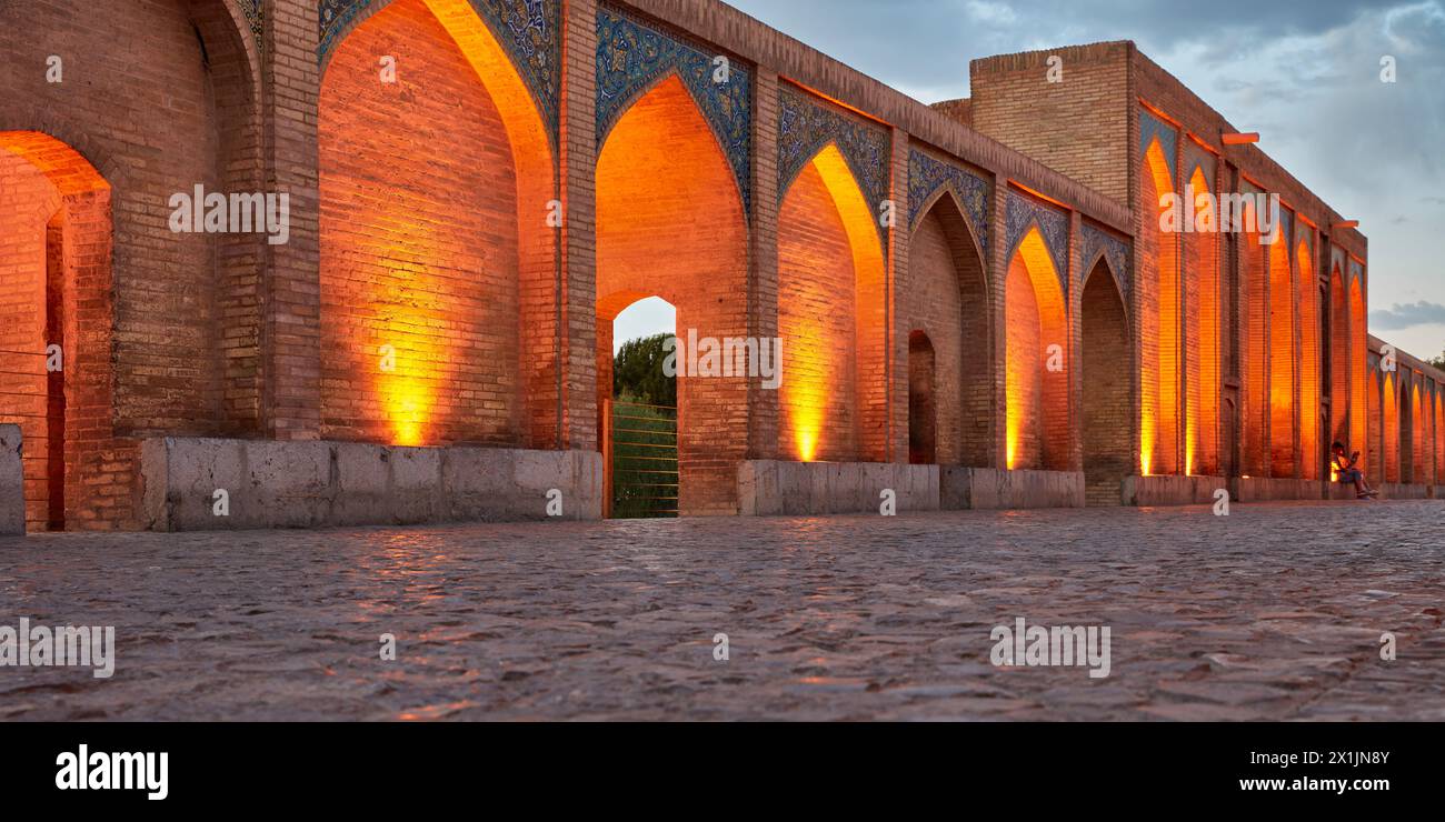 Vista panoramica degli archi a volta illuminati del Ponte Khaju del XVII secolo sul fiume Zayanderud al crepuscolo. Isfahan, Iran. Foto Stock