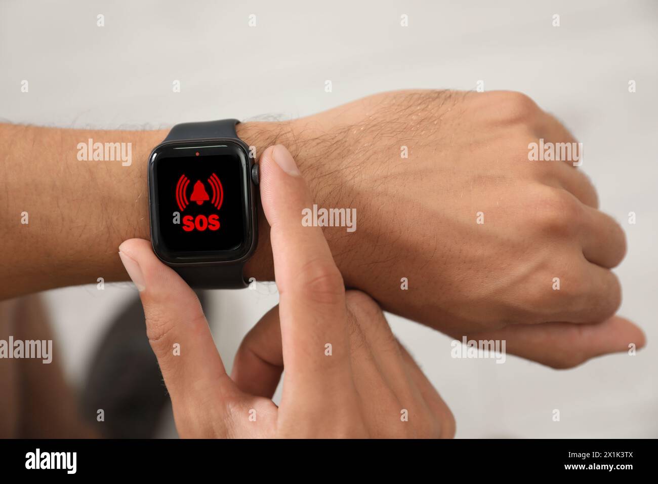 Uomo che utilizza la funzione SOS su uno smartwatch in interni, primo piano Foto Stock