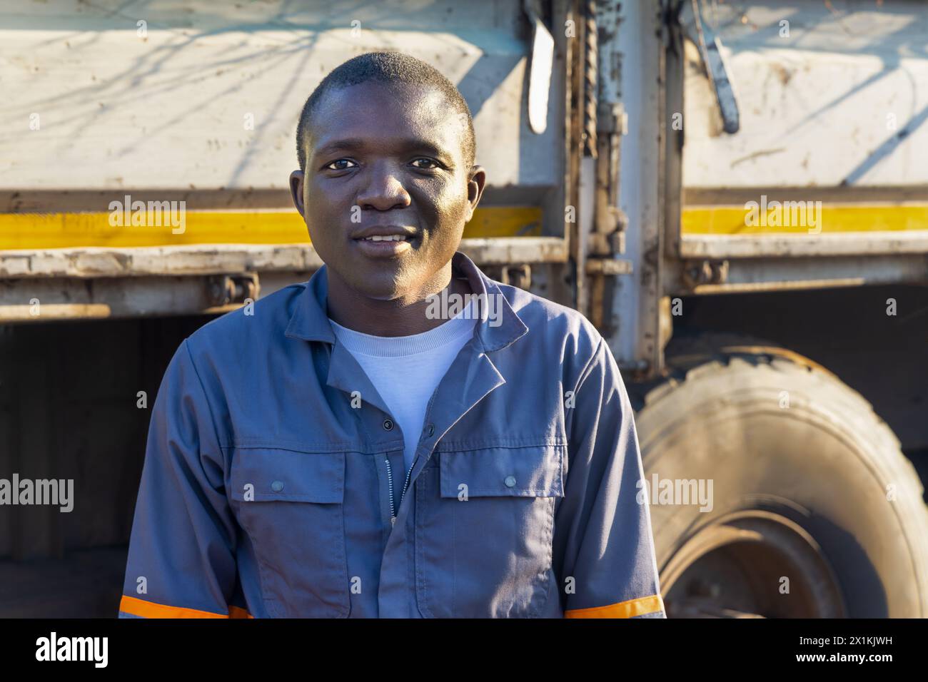 giovane autista africano in abbigliamento da lavoro, accanto al camion Foto Stock
