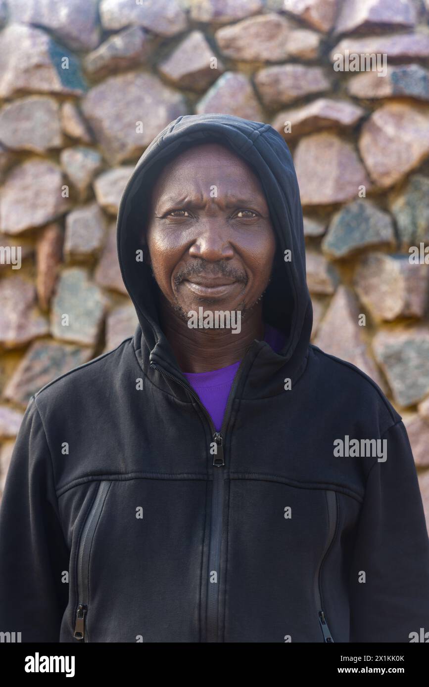 uomo africano adulto con felpa con cappuccio, muro di pietra sullo sfondo Foto Stock