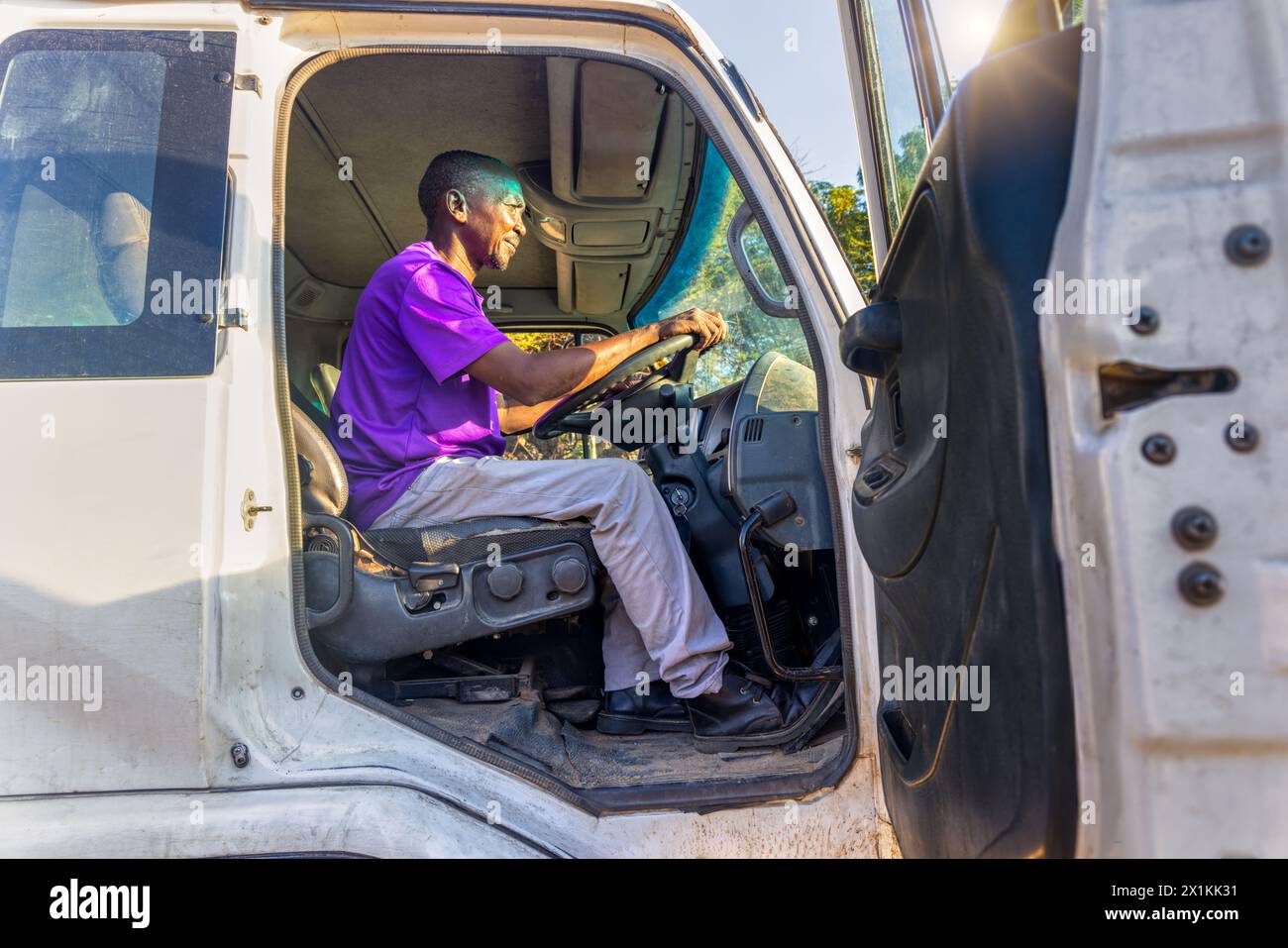 conducente africano nella cabina del carrello posto sul sedile di fronte al volante Foto Stock