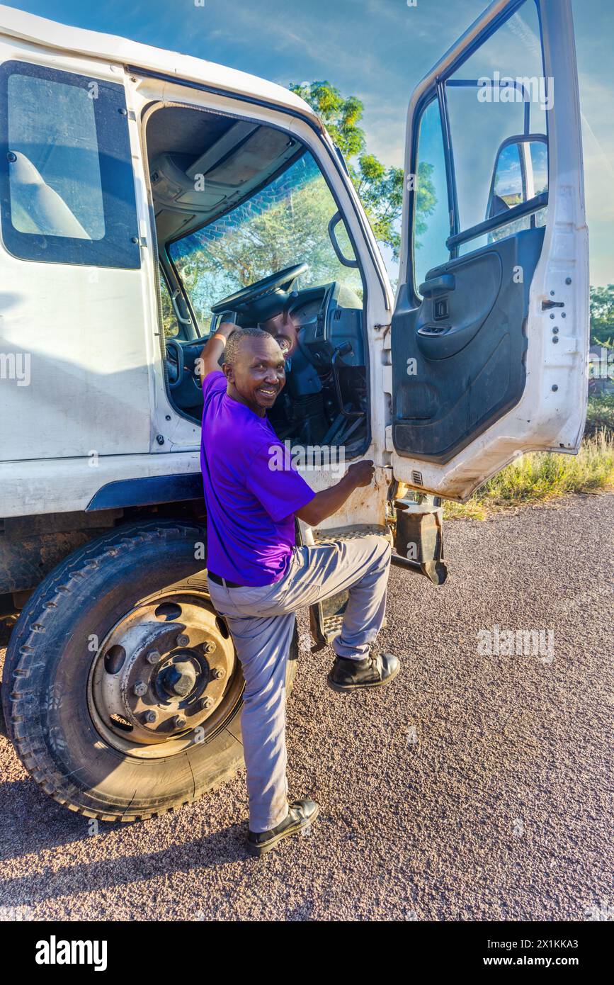 autista africano entrare nella cabina del veicolo , vista profilo, trasporto in città Foto Stock