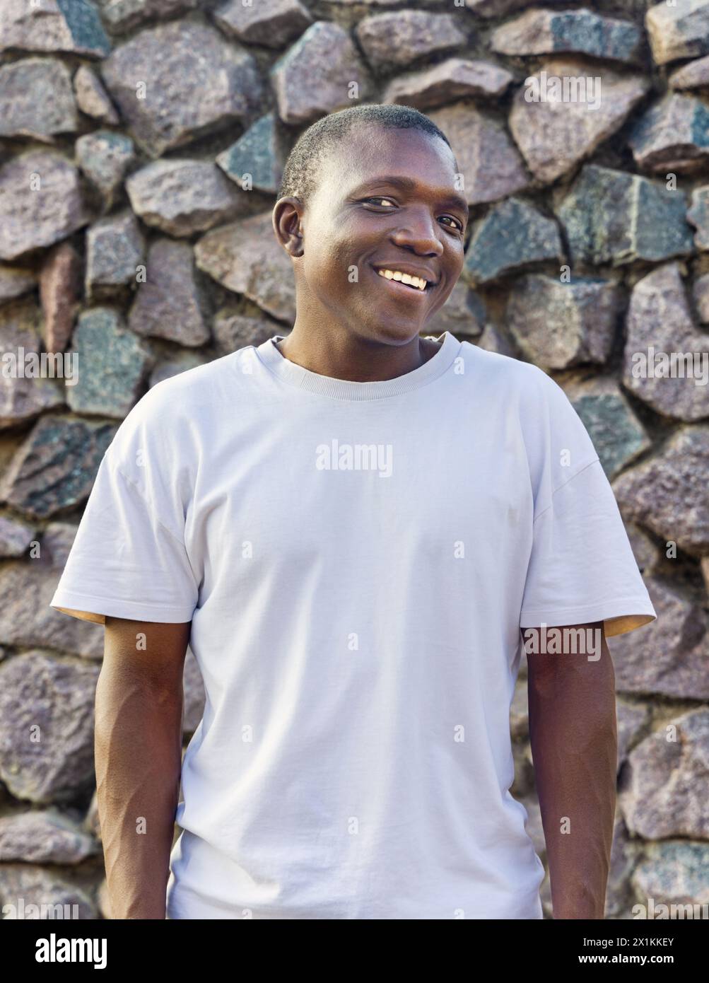 giovane africano sorridente con abbigliamento casual, sfondo in pietra Foto Stock