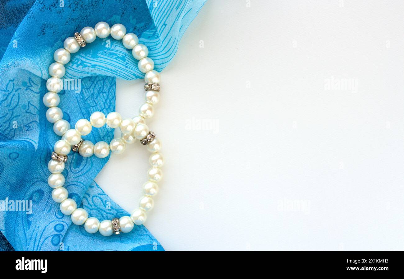 Due bracciali in avorio con perle sintetiche su tessuto blu, sfondo bianco con spazio per la copia Foto Stock