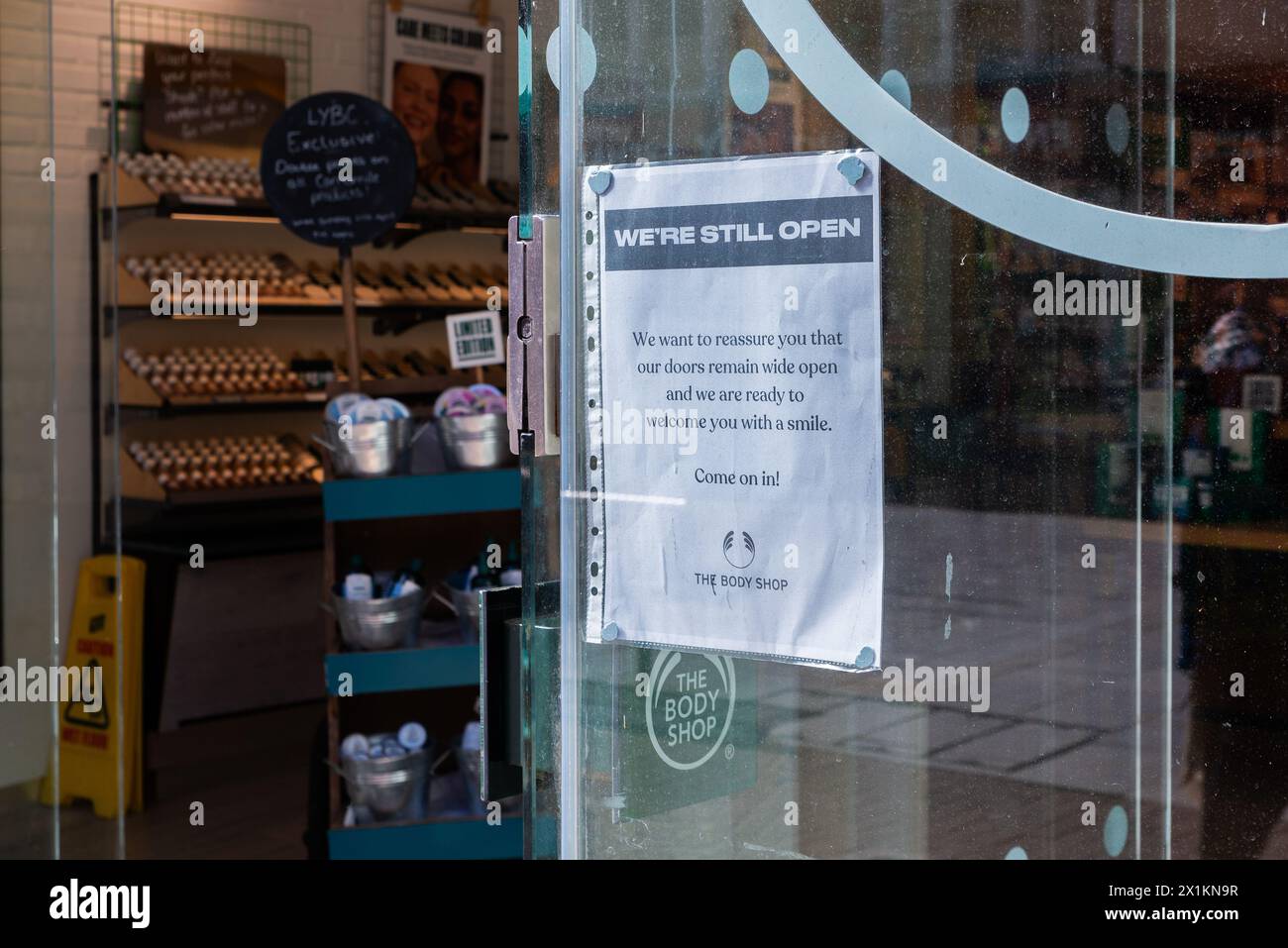 Avviso sulla finestra della filiale Body Shop che informa i clienti che sono ancora aperti nonostante il marchio sia in fase di amministrazione. Siamo ancora aperti Foto Stock