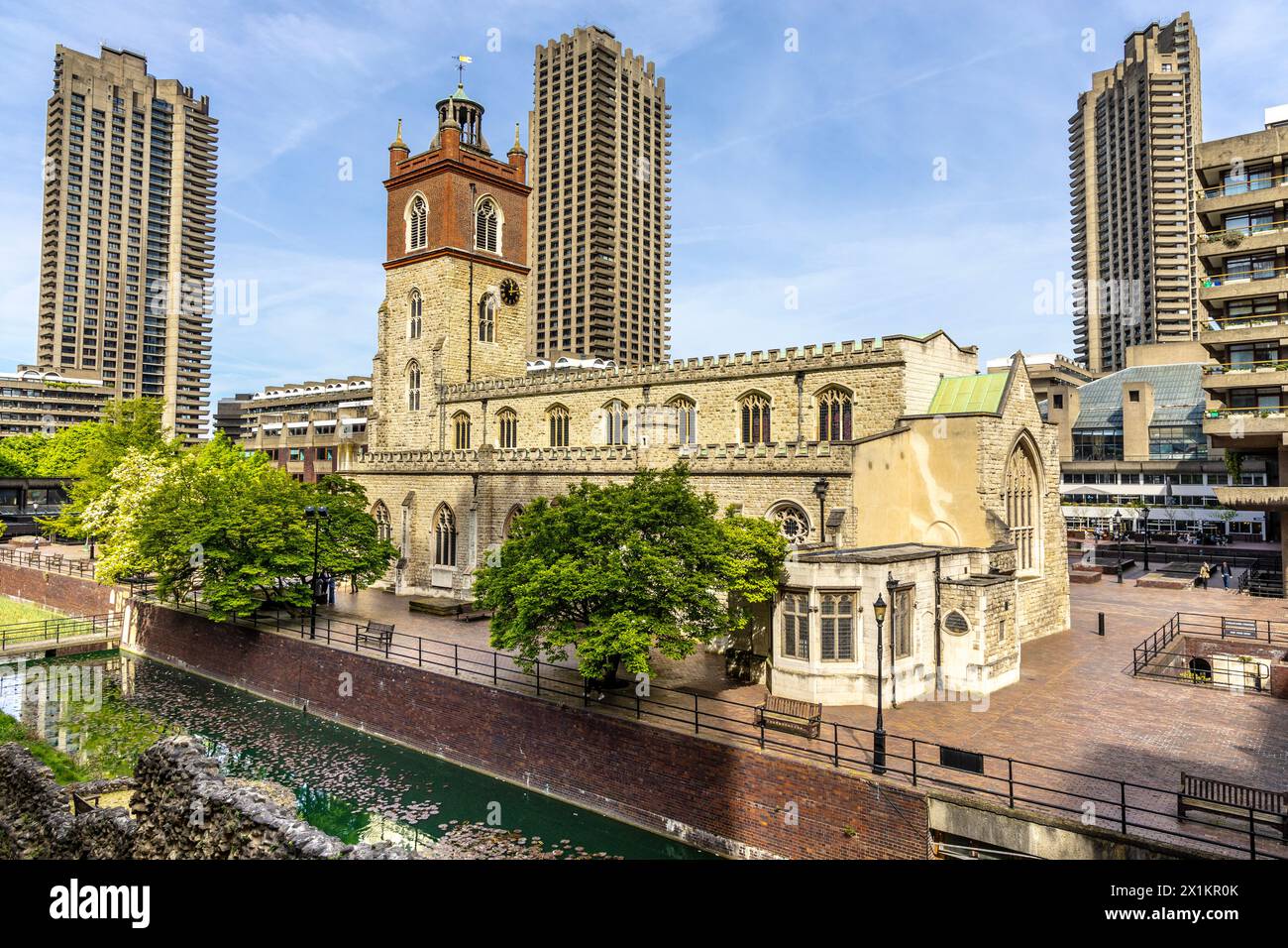 Chiesa medievale di St Giles Cripplegate situata nella Barbican Estate, con alte torri brutaliste sullo sfondo, Londra, Inghilterra Foto Stock