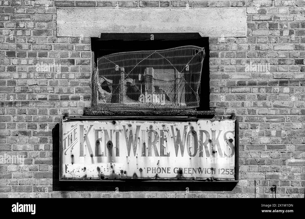 Fotografia d'archivio in bianco e nero degli anni '1990 del vecchio cartello metallico per la Kent Wire Works sulla riva sud del Tamigi tra Greenwich e Deptford. Foto Stock